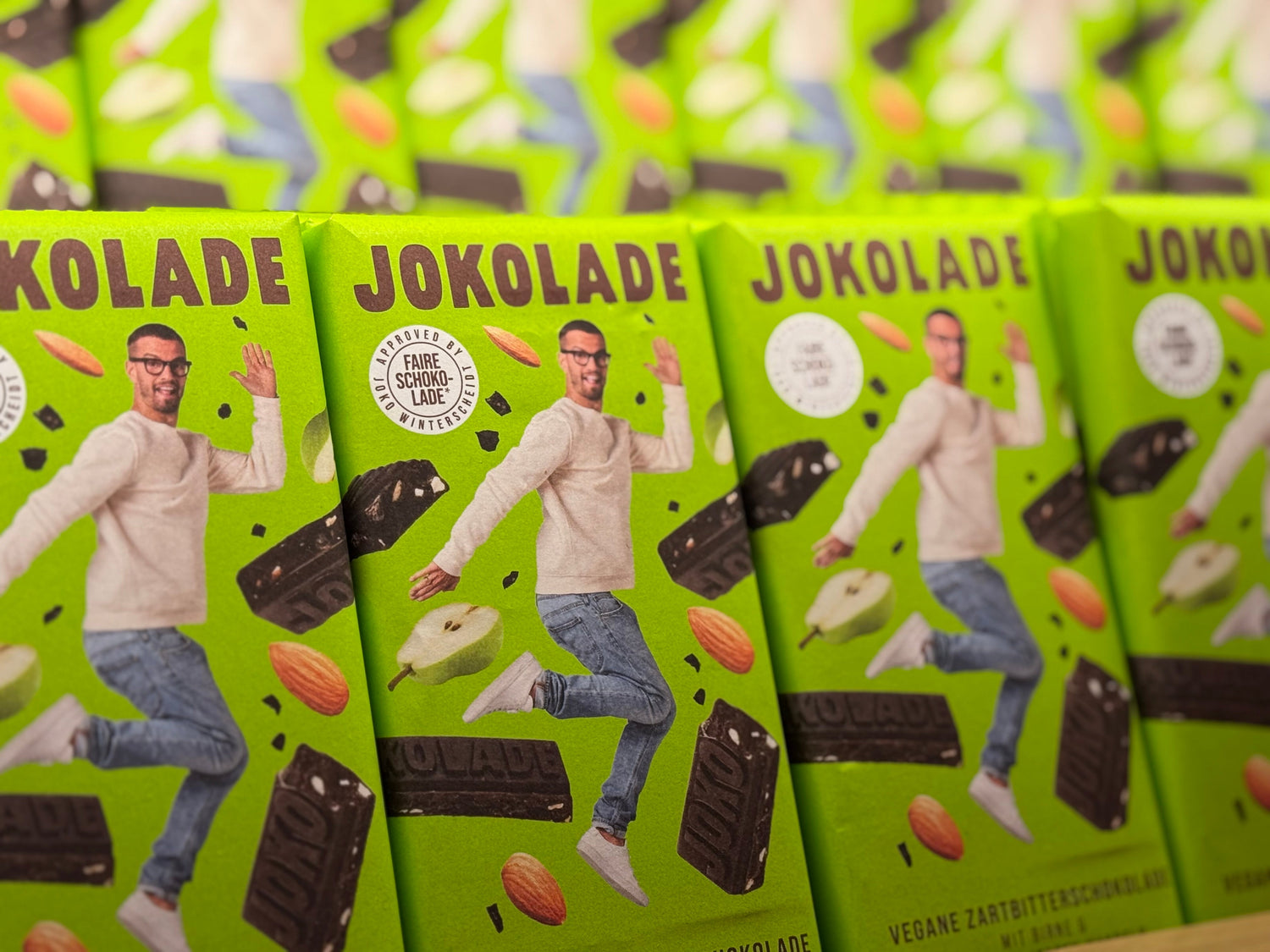 Grüne Verpackung der Jokolade mit springender Person und abgebildeten Zutaten, mehrfach hintereinander gestapelt.