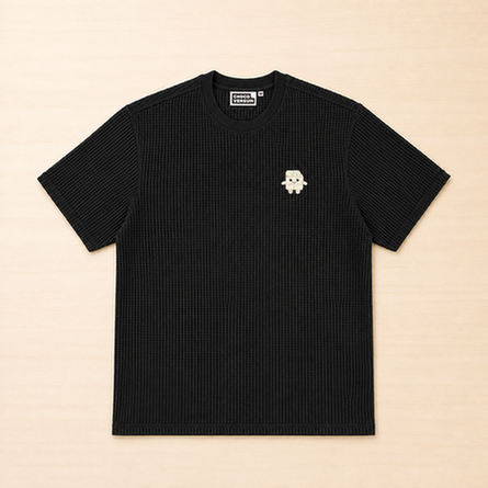 Schwarzes T-Shirt mit Waffelstruktur und kleiner aufgestickter Schokoladenfigur auf der linken Brust.