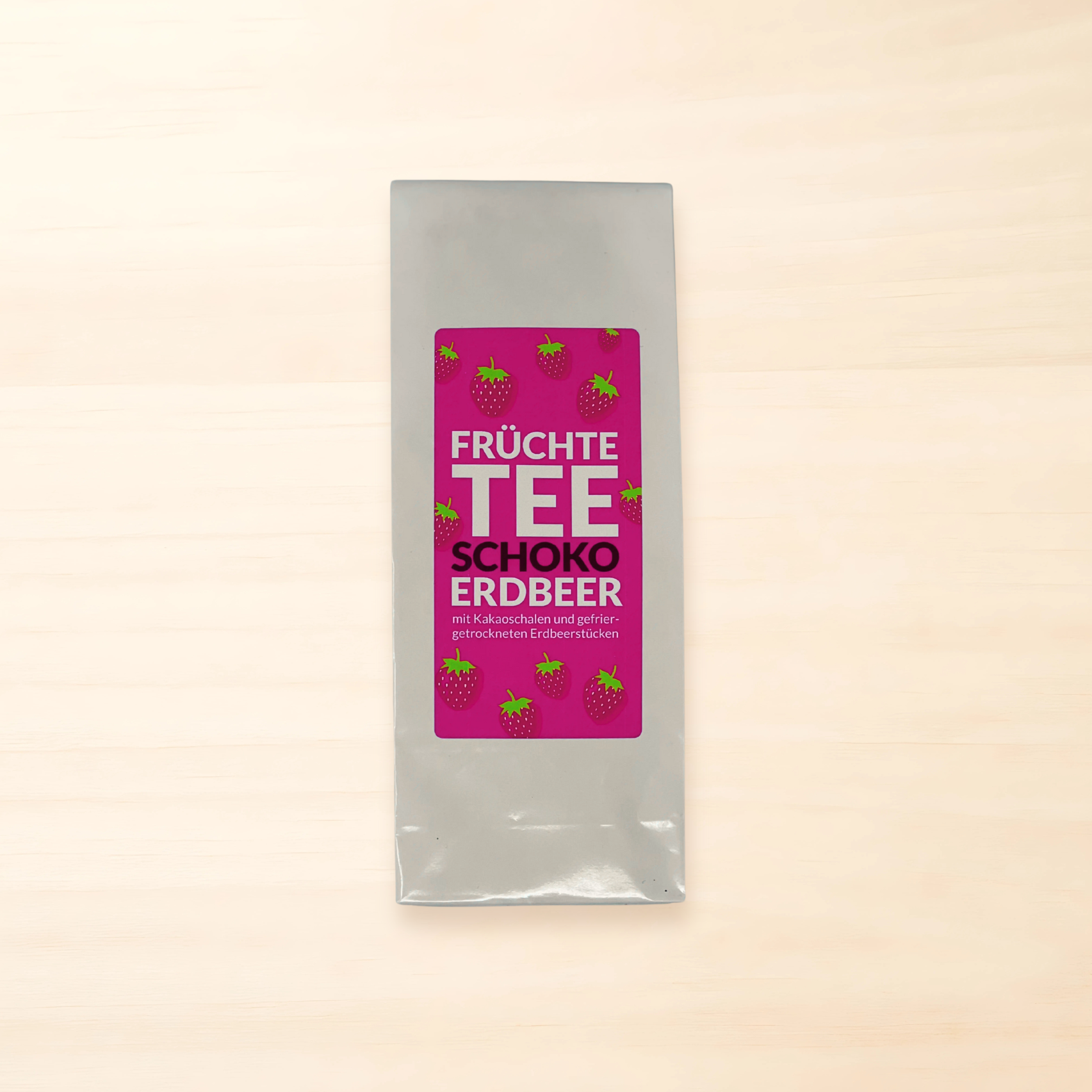 Weißer Teebeutel mit pinkem Etikett, Erdbeerillustrationen und der Aufschrift „Früchtetee Schoko-Erdbeer“.
