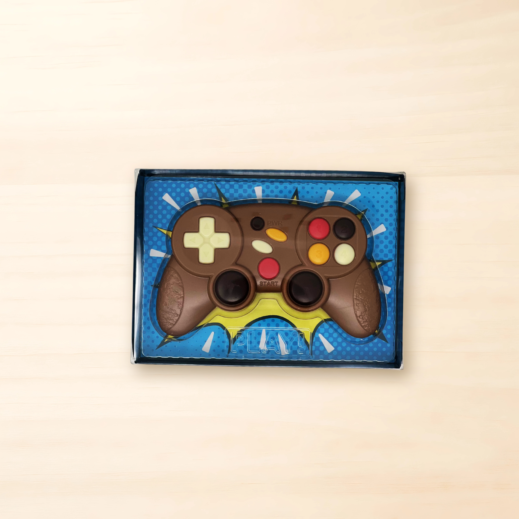 Schokoladenfigur in Form eines Game-Controllers aus Vollmilchschokolade mit bunten dekorierten Tasten in Verpackung.