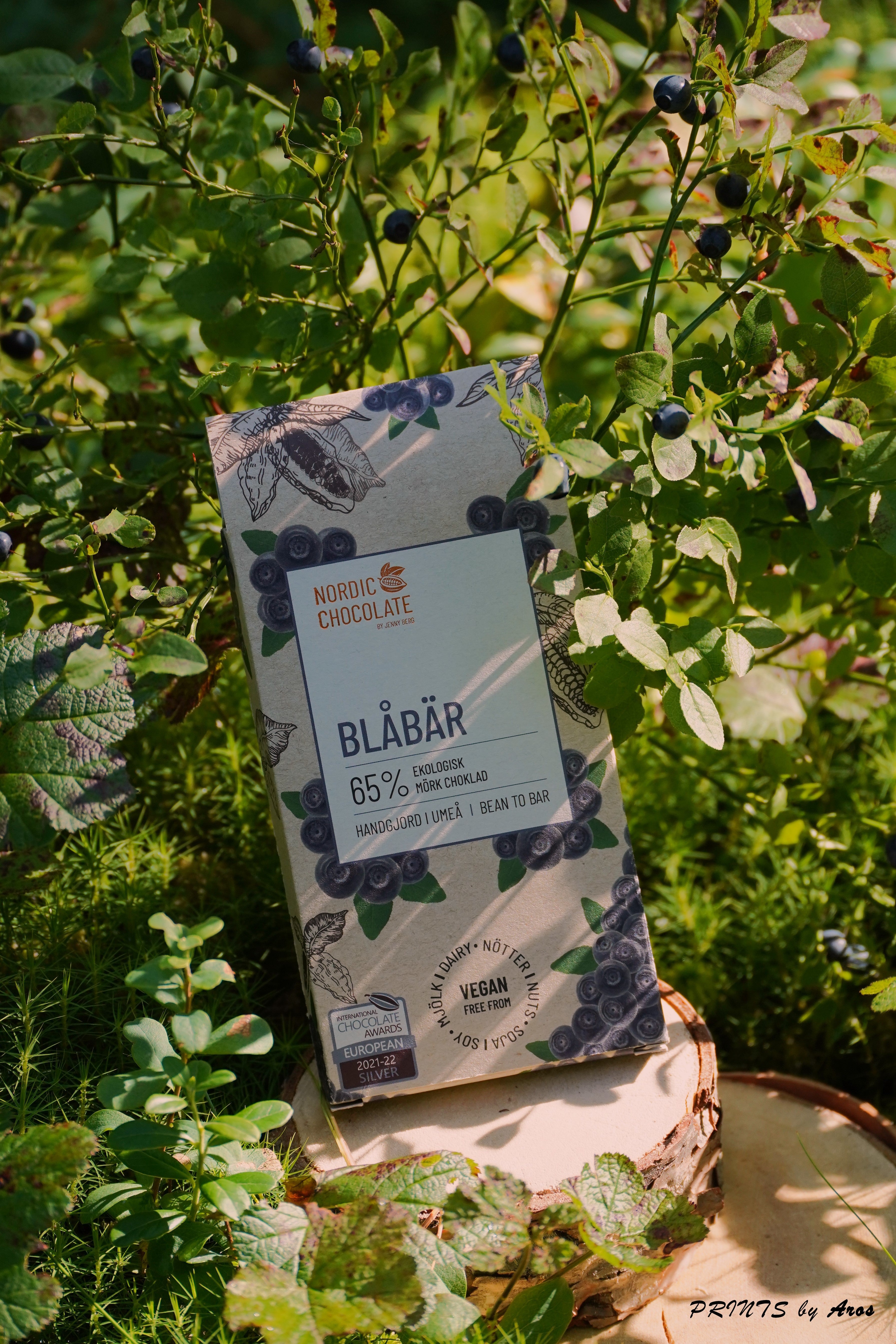 Blaubeerschokolade - Verpackung mit Heidelbeeren und Kakaofrucht unter Blaubeerstrauch