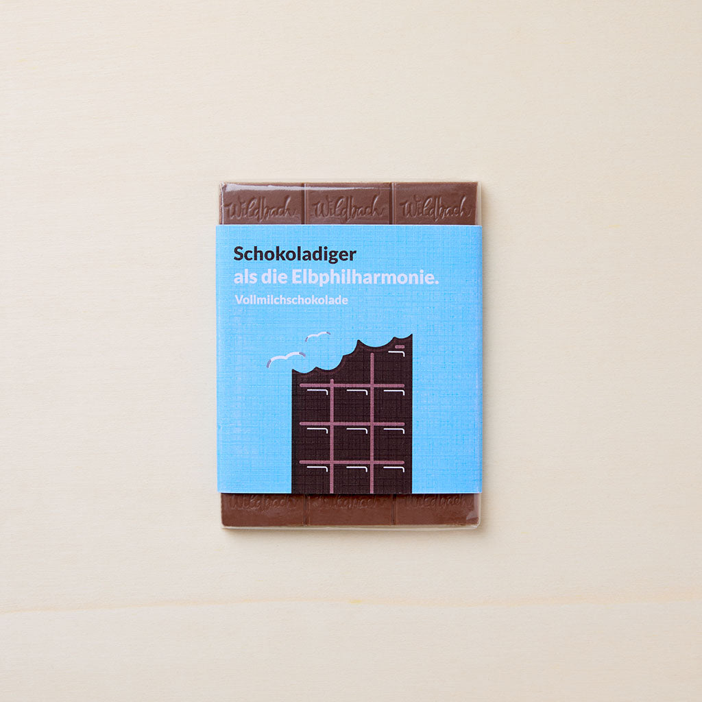 Vollmilchschokolade in blauem Wickler mit grafischen Elbphilharmonie-Motiv im Schokoladendesign und Artikelbezeichnung in brauner und weißer Schriftfarbe