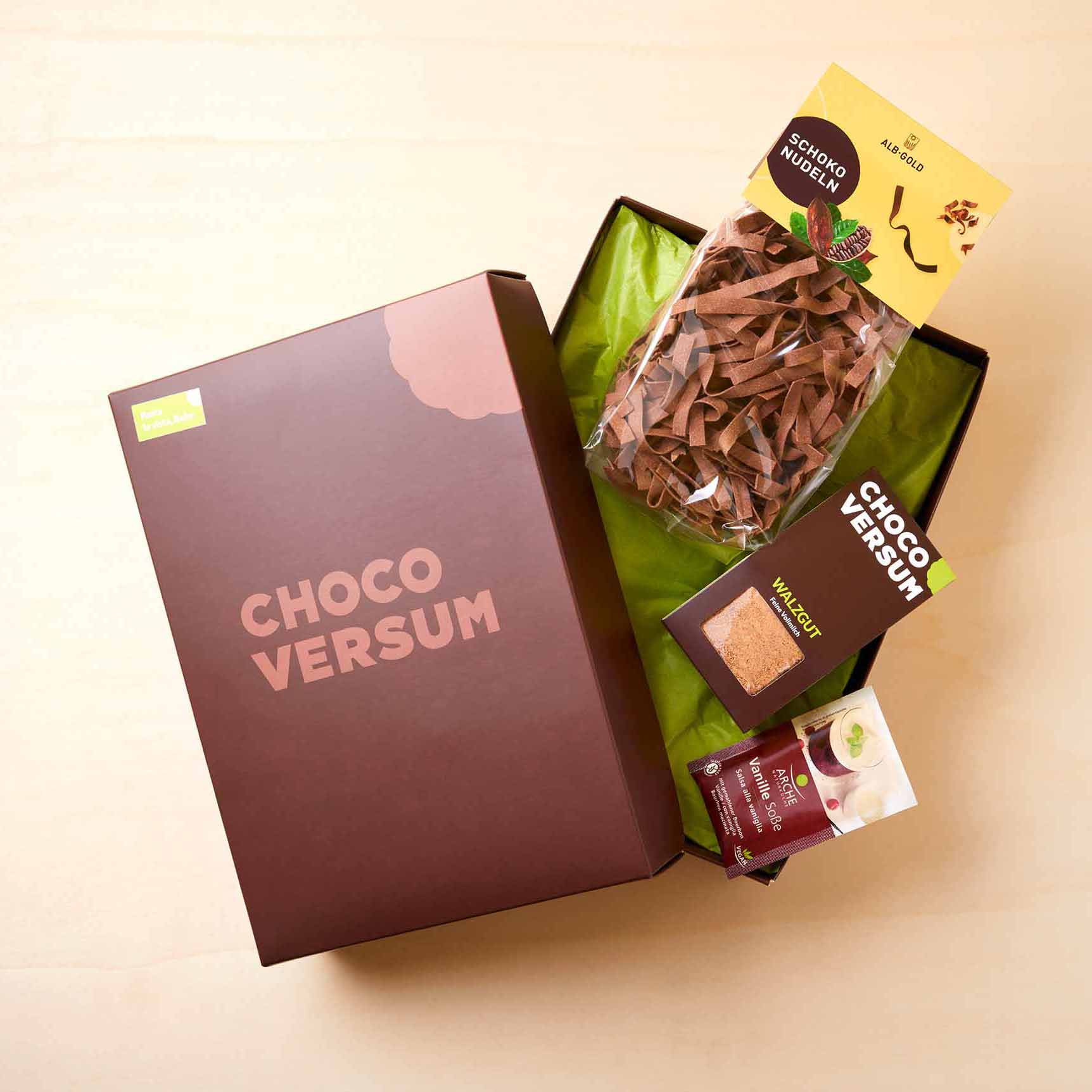 braune Präsentbox mit Schokonudeln, Vanille-Sauce und einer Packung Walzgut im Chocoversum
