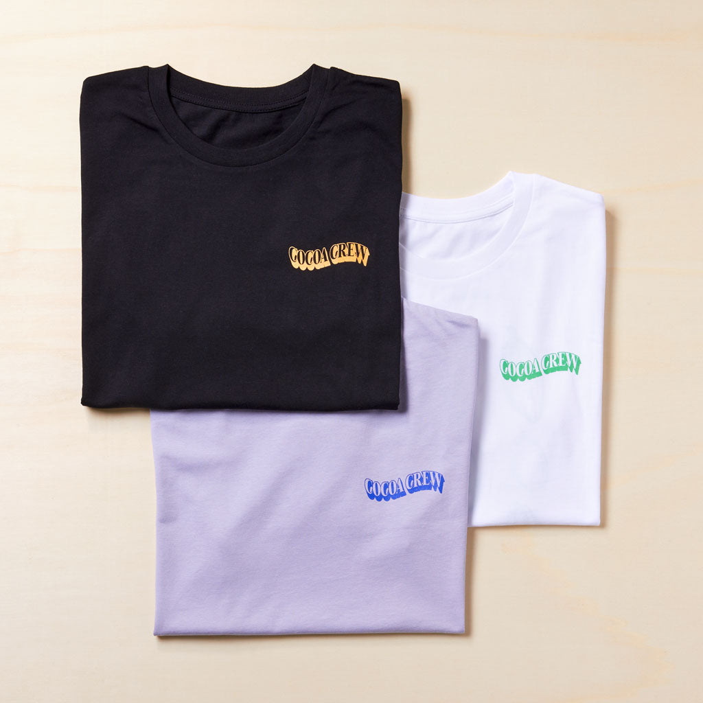 3 T-Shirts gefaltet in den Farben schwarz, flieder und weiß mit Cocoa Crew Aufdruck