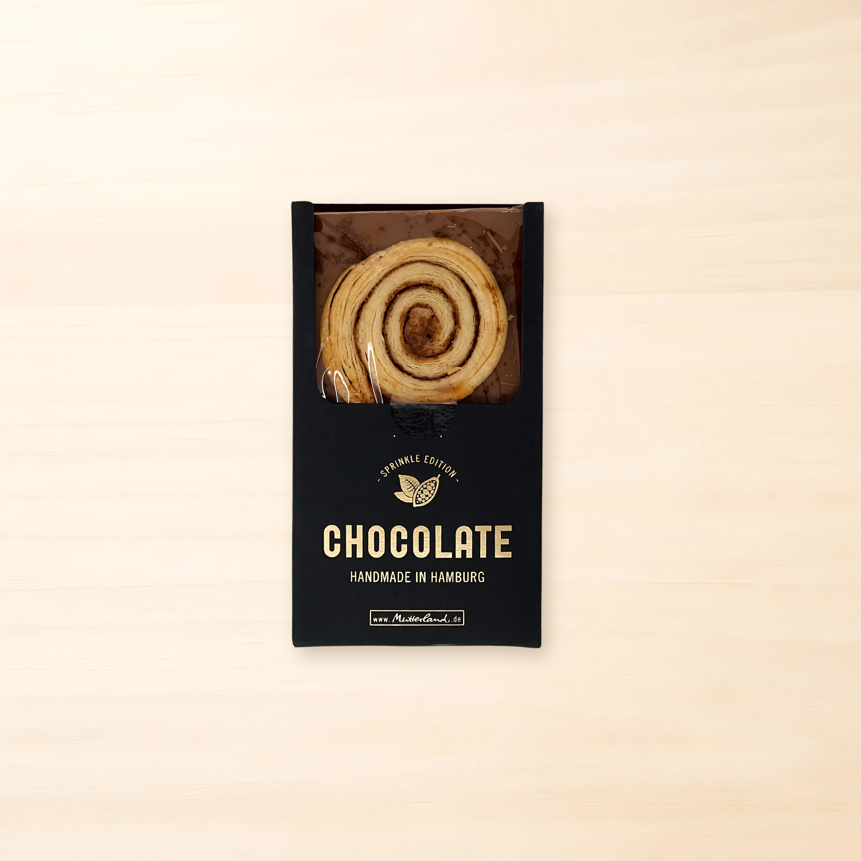 Tafel Vollmilchschokolade mit eingebackenem Franzbrötchen, in eleganter schwarzer Verpackung mit goldener Schrift "Handmade in Hamburg".