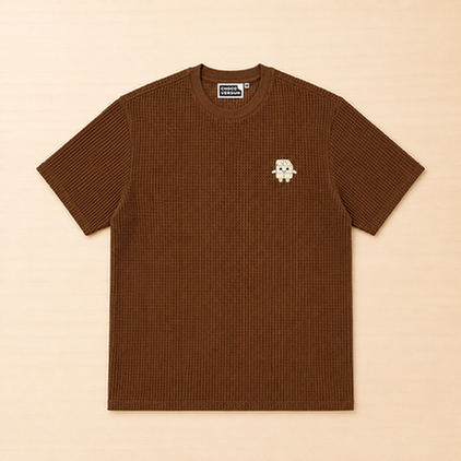 Braunes T-Shirt mit Waffelstruktur und kleiner aufgestickter Schokoladenfigur auf der linken Brust.