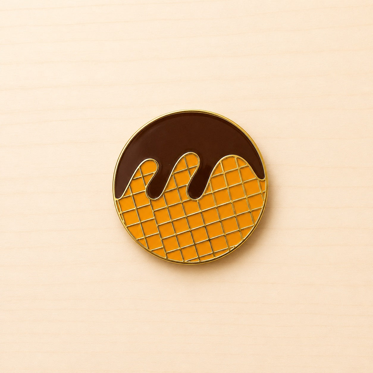 Runder Metall-Ansteck-Pin mit orangefarbenem Waffelmuster, brauner Schokoladenoptik und goldfarbener Umrandung.