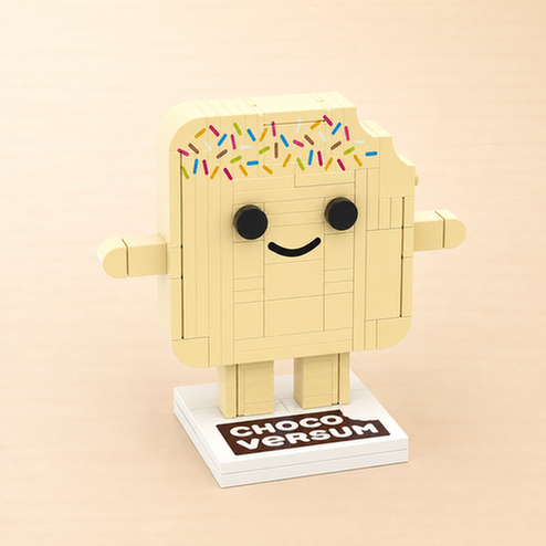 Klemmbaustein-Figur „Sprinkles“, eine lächelnde weiße Schokoladentafel mit bunten Zuckerstreuseln, auf weißem Standfuß mit CHOCOVERSUM-Logo.
