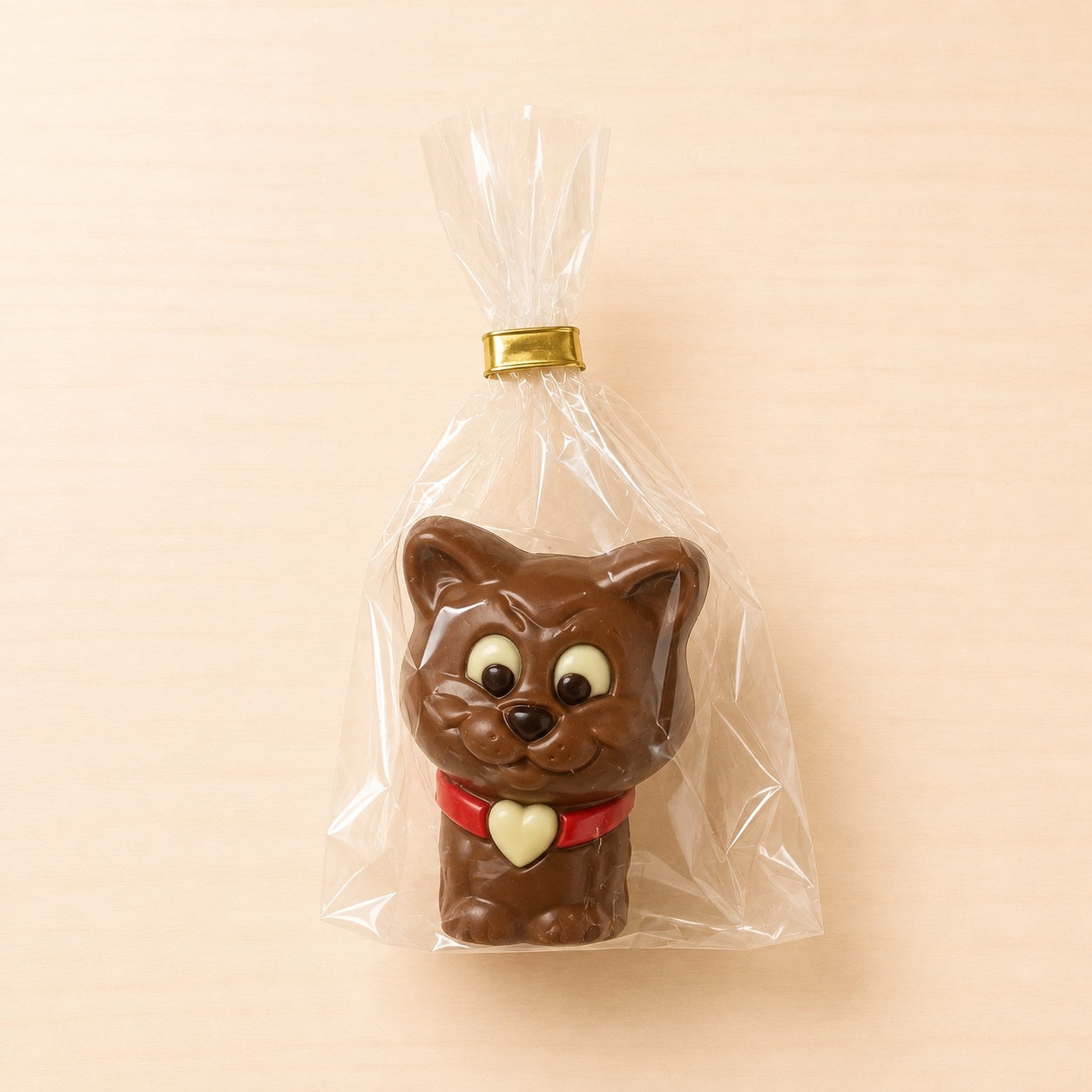 Schokoladenfigur in Form einer braunen Katze mit rotem Halsband und Herzanhänger, einzeln verpackt.