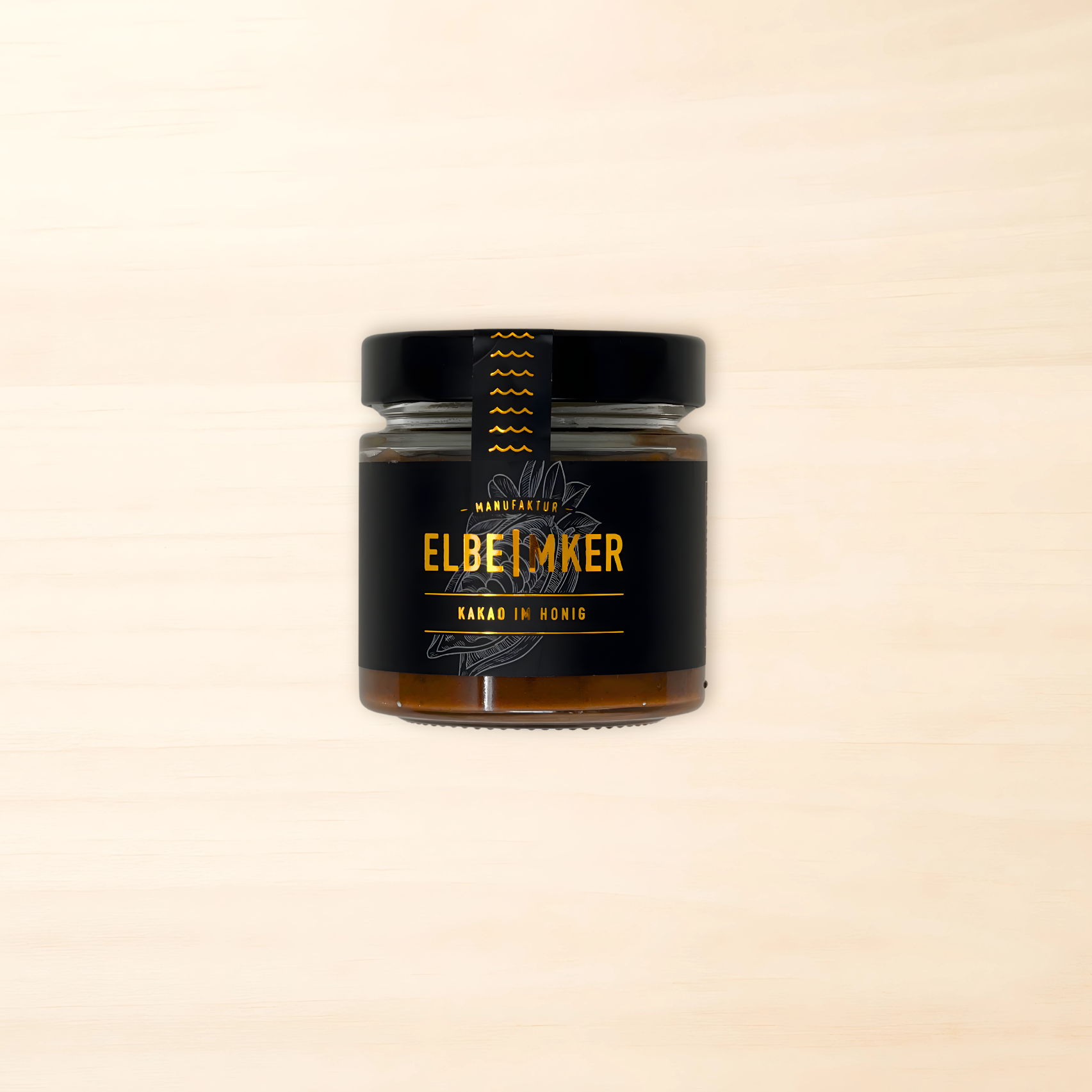 Elbeimker-Kakao-Honig Glas mit schwarzem Etikett mit weißer kakao-BohnenZeichnung und kupferfarbener Schrift. Schwarzer Deckel - Inhalt Honig mit brauner Färbung durch den Kakao.