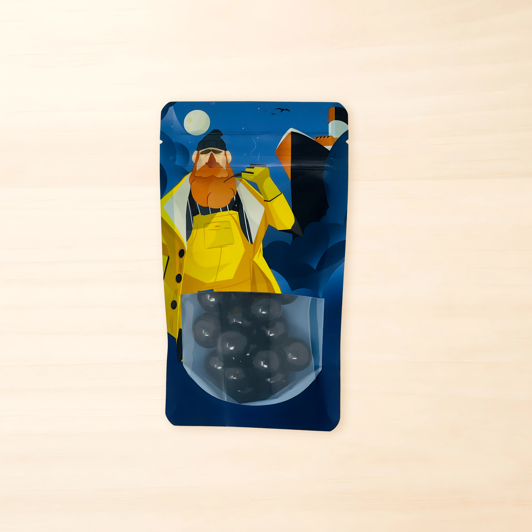 Beutel mit maritimem Design und einem bärtigen Seemann darauf, unten Sichtfenster mit schokolierten Lakritzkugeln.