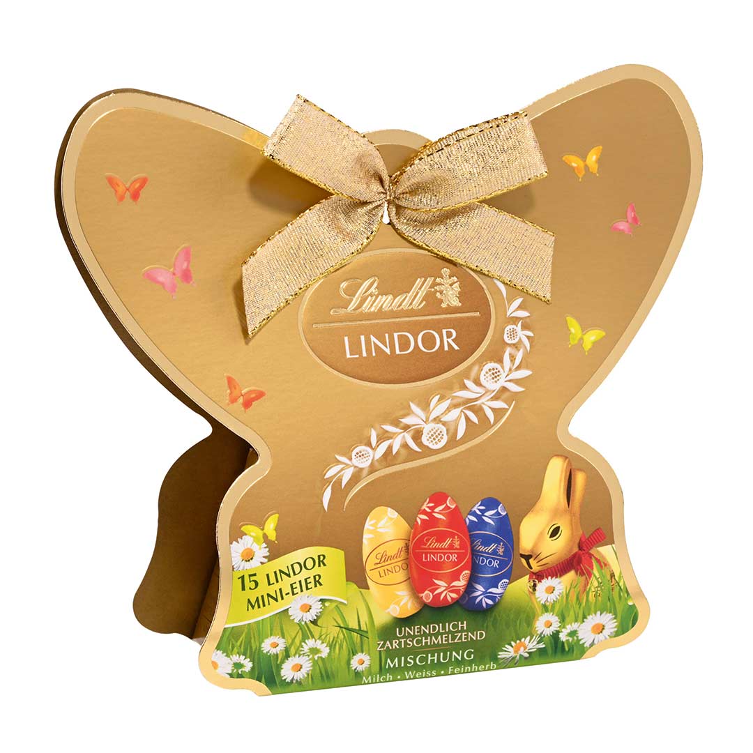 Goldene Lindorverpackung in Schmetterlingsform mit abgebildeter Frühlingswiese, Lindoreiern und Goldhase