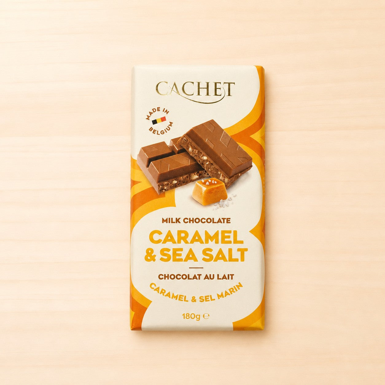 Verpackte Tafel Cachet Vollmilchschokolade „Caramel & Sea Salt“ (180 g) mit Abbildung von Schokoladenstücken, Karamell und Meersalz auf hellem Hintergrund.