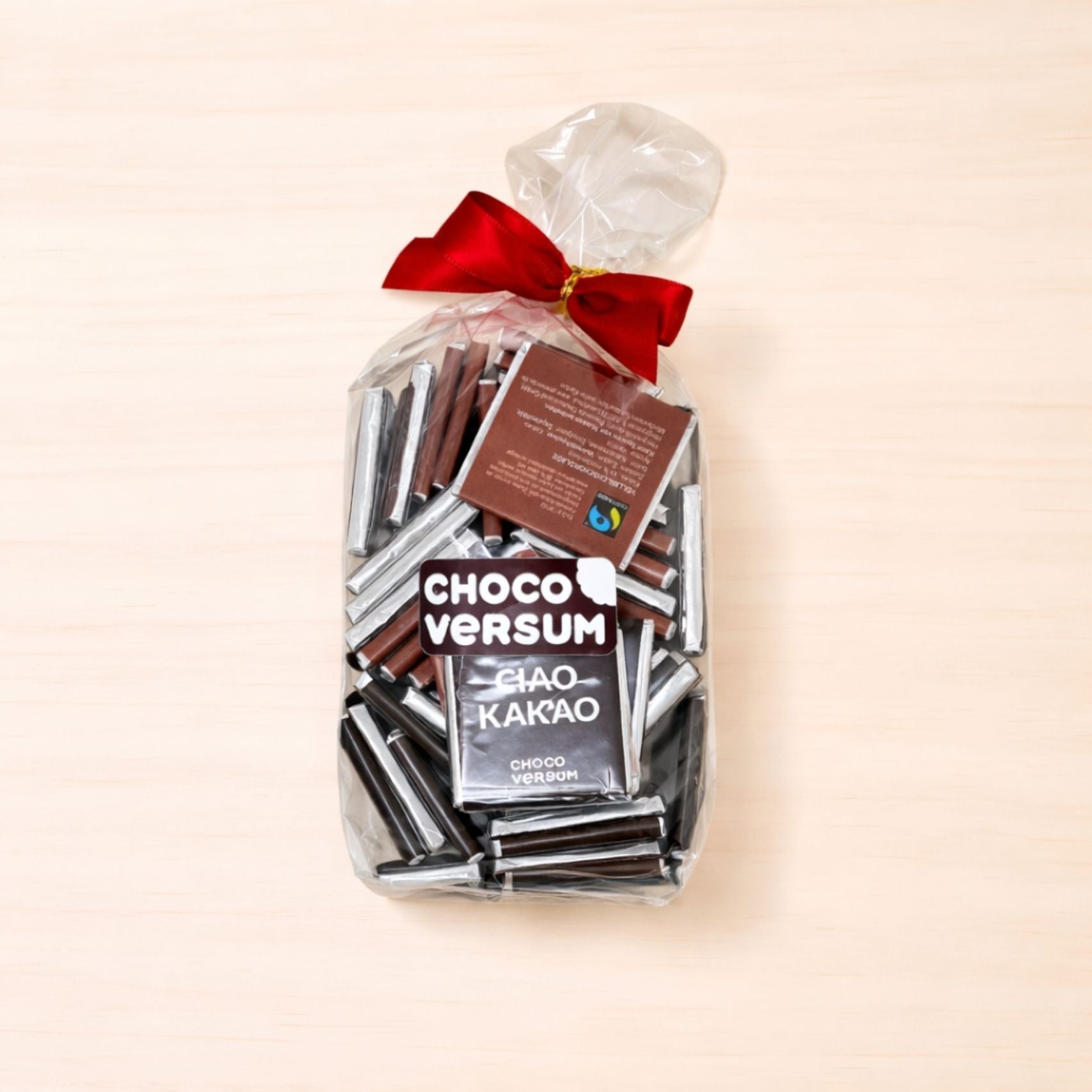 Geschenkbeutel mit roter Schleife, gefüllt mit einzeln verpackten CHOCOVERSUM-Schokoladentäfelchen „Ciao Kakao“ in Vollmilch- und Zartbitterschokolade.