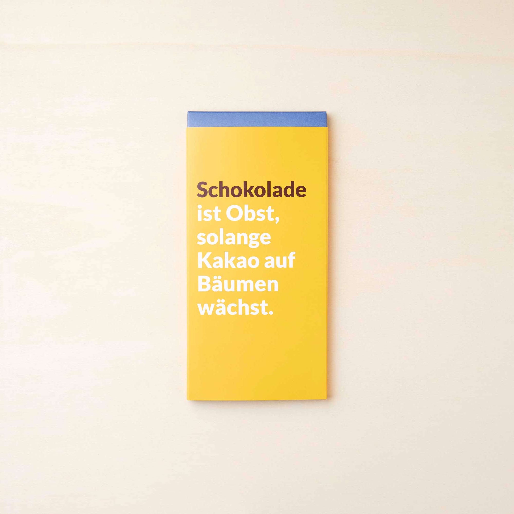 Extra cremige Vollmilchschokolade von Lindt in einer gelben Verpackung mit dem Spruch: "Schokolade ist Obst, solange Kakao auf Bäumen wächst".