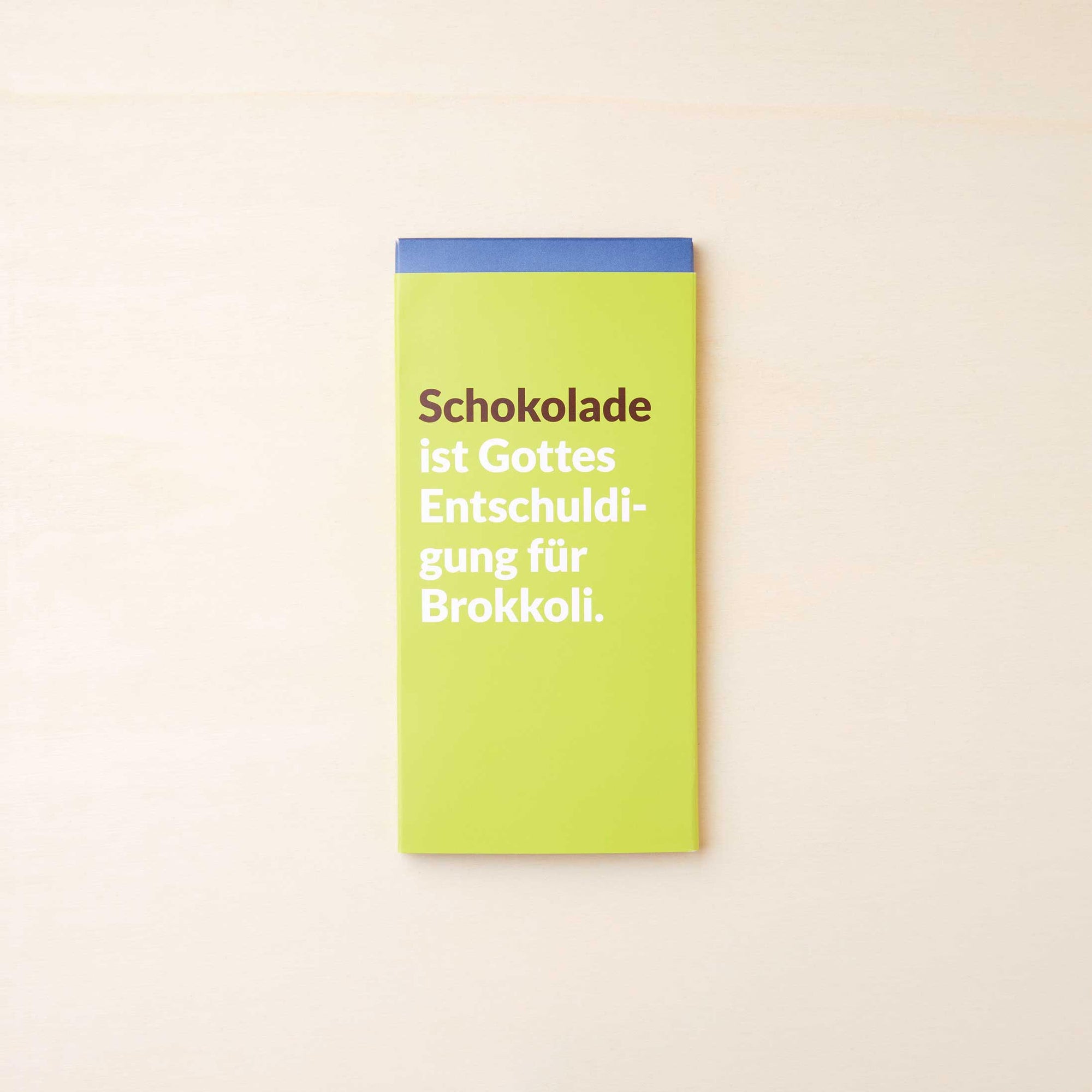 Extra cremige Vollmilchschokolade von Lindt in einer grünen Verpackung mit dem Spruch: "Schokolade ist Gottes Entschuldigung für Brokkoli".