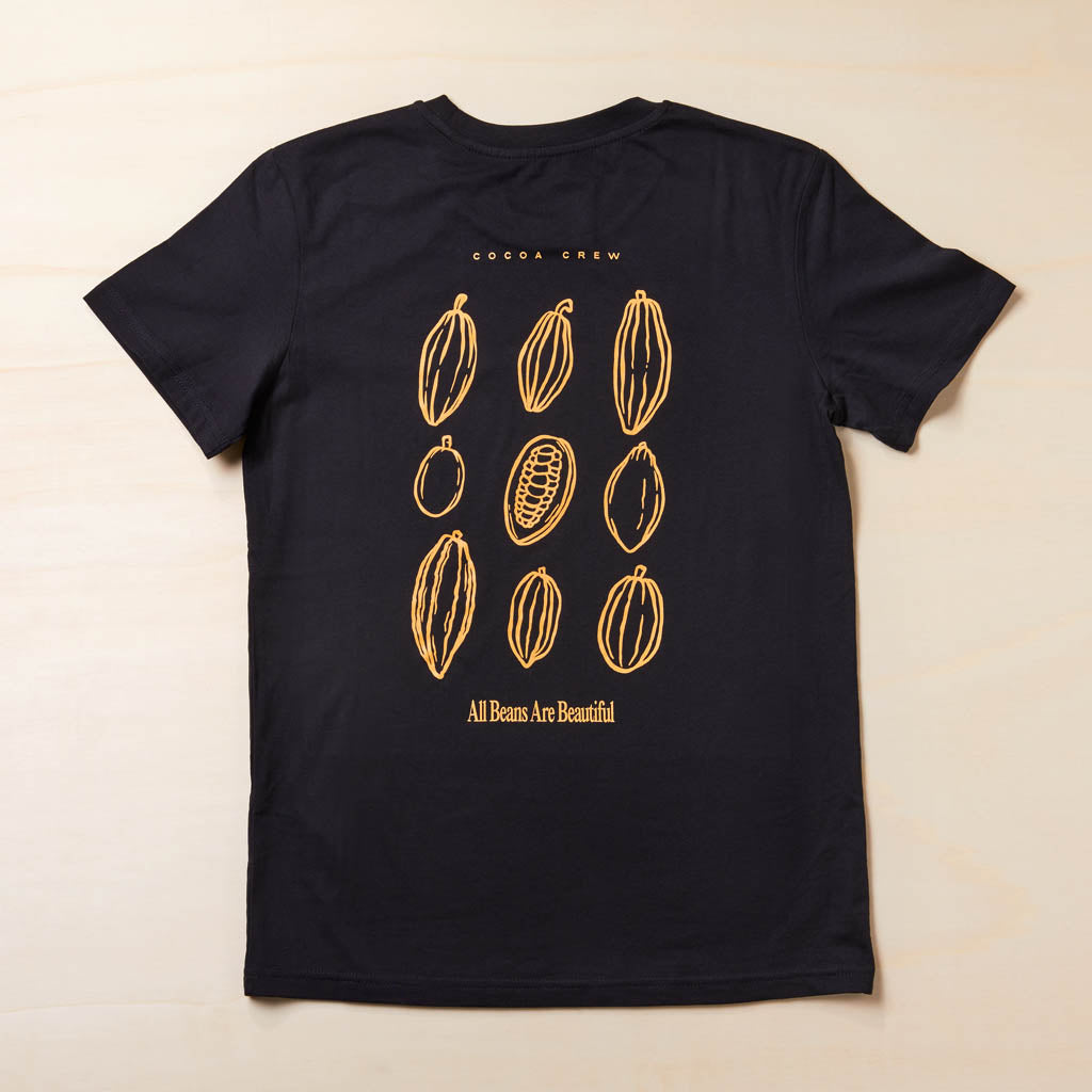 schwarzes T-Shirt Rückseite mit orangem Aufdruck Cocoa Crew"All Beans Are Beautiful" und unterschiedliche Kakaofrüchte