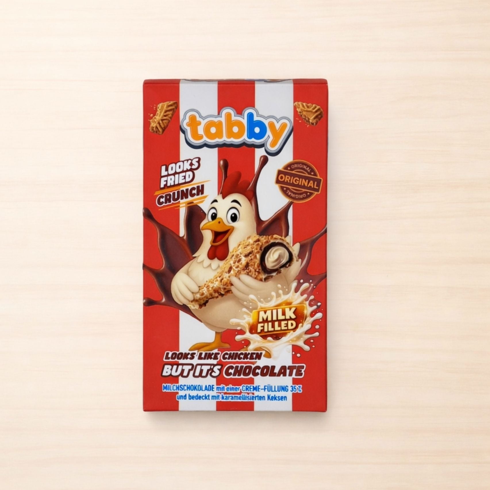 Schokoladenriegel in Form eines panierten Hähnchenschenkels mit cremiger Füllung in roter Verpackung mit Comic-Huhn und Streifenmuster